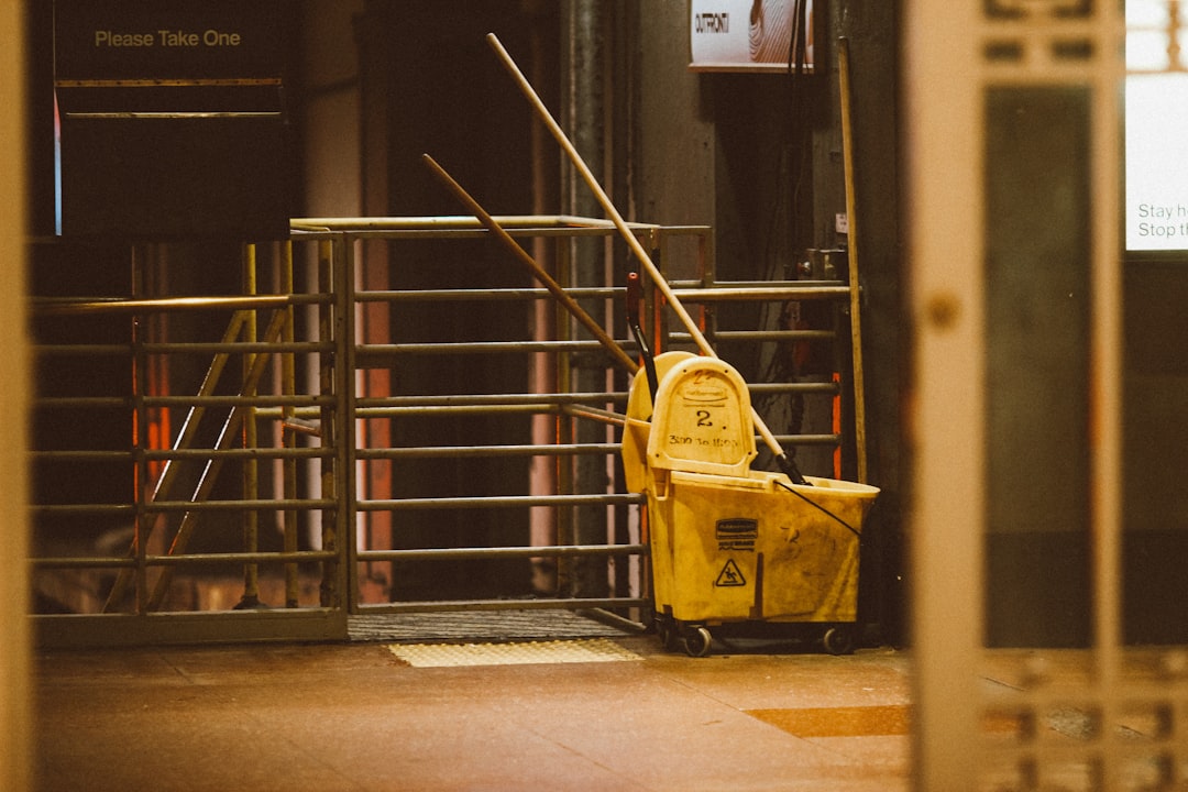 yellow-plastic-trash-bin-beside-black-metal-stair-railings-fstor-ixw